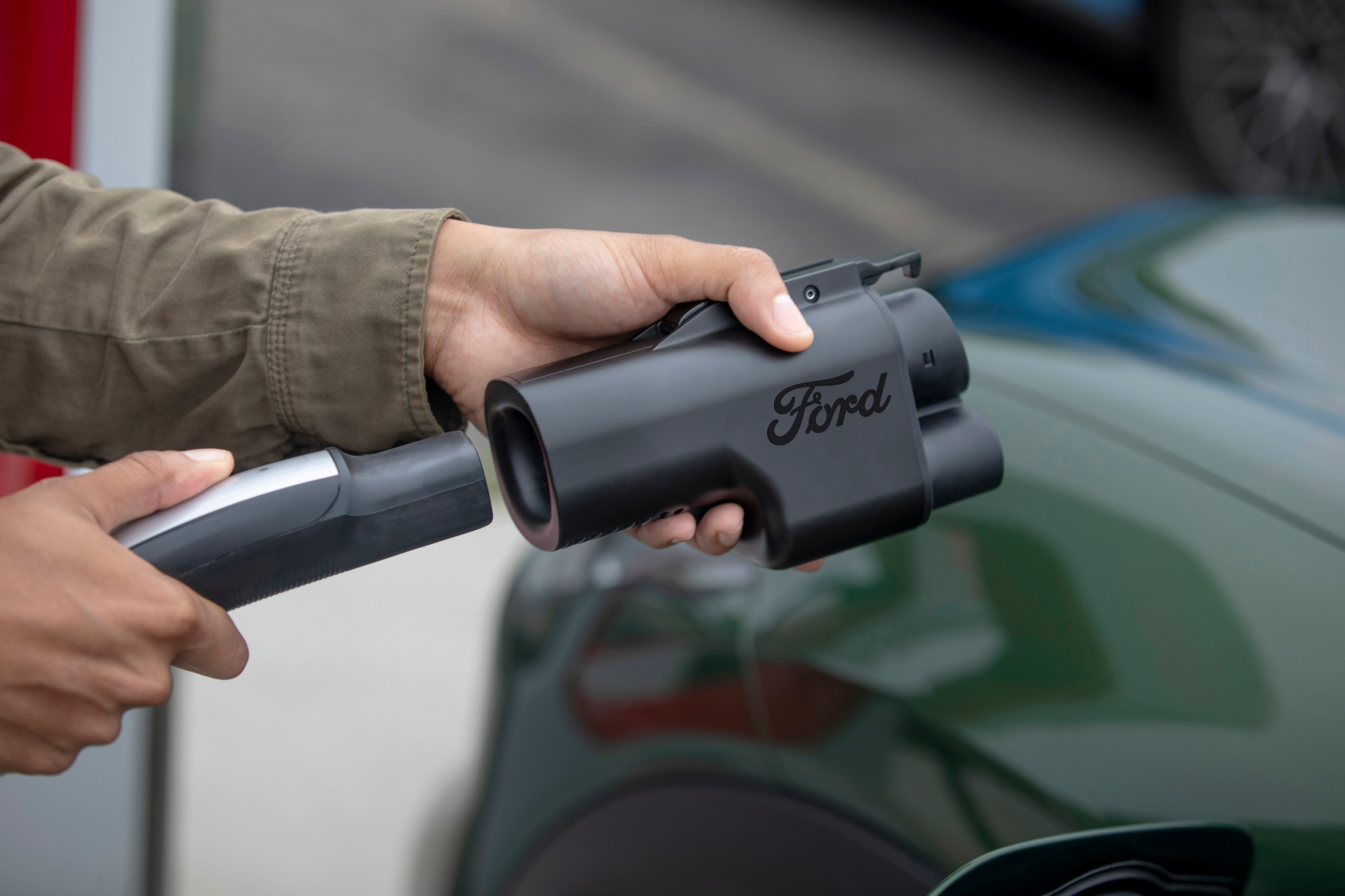 Someone places a Ford charging adapter on the charger cable.